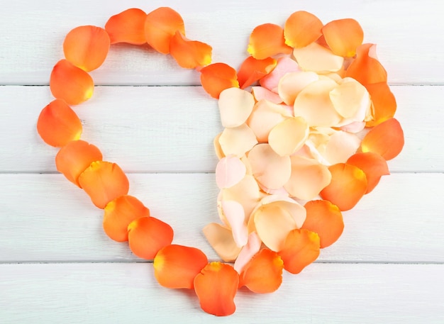 Beautiful heart of rose petals on wooden background