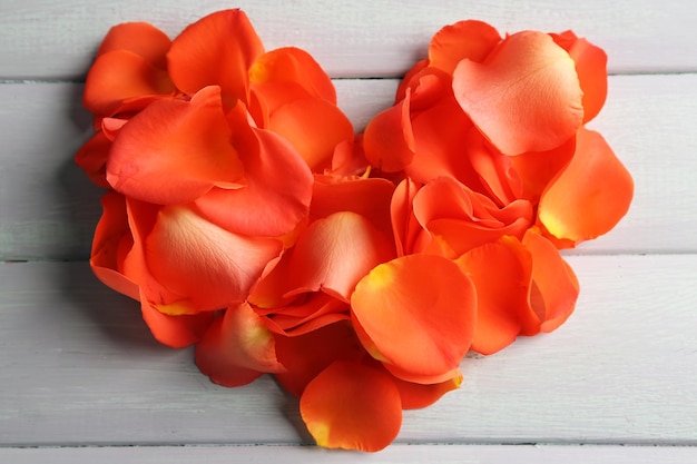 Beautiful heart of rose petals on wooden background