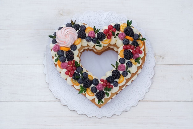 Beautiful heart shaped cake with fresh berries for Valentine's day on white wooden table