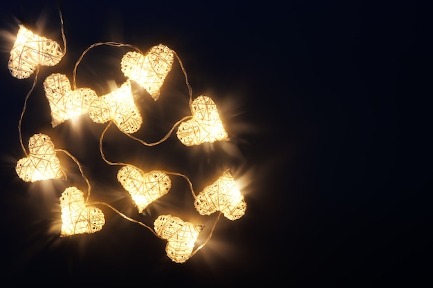 Beautiful heart-shaped fairy lights glowing on dark. St. Valentine's Day background