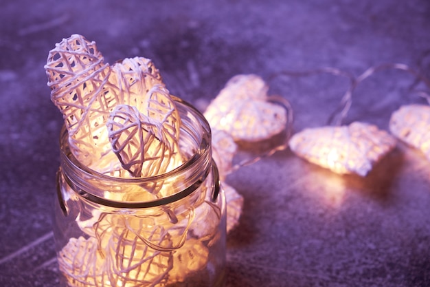 Beautiful heart-shaped fairy lights glowing inside glass jar. St. Valentine's Day mood