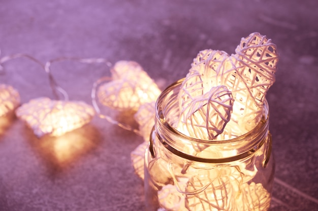 Beautiful heart-shaped fairy lights glowing inside glass jar. St. Valentine's Day mood