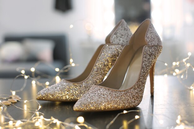 Beautiful high heeled shoes on table with fairy lights