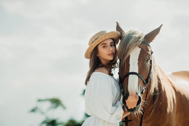 牧場の背景、正面に馬と美しいヒッピーの女の子。帽子の少女。ソフトフォーカス