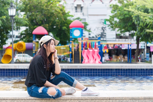 Beautiful hipster girl sit on the park for relaxLifestyle of single womanPortrait of asian people with backpack