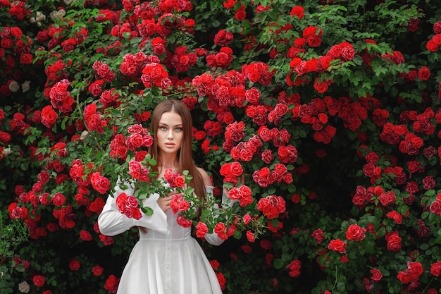 красивая хипстерша в цветущем кусте с белыми цветами спиреи бохо девушка в цветочном