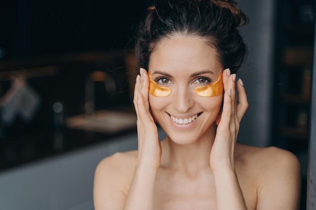 Beautiful hispanic girl doing spa procedures Lady applies patches touches temples and eyes skin