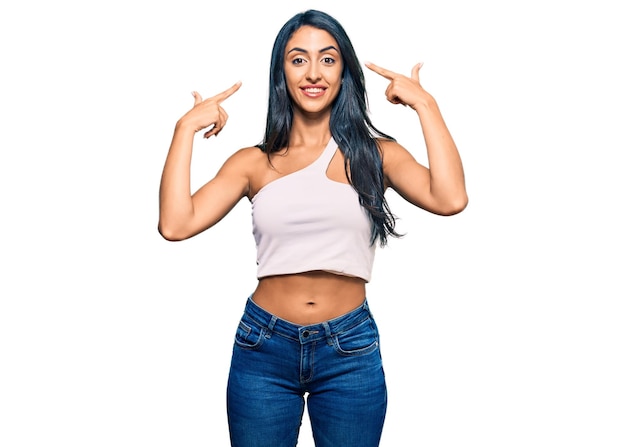 Beautiful hispanic woman wearing casual clothes smiling pointing to head with both hands finger great idea or thought good memory