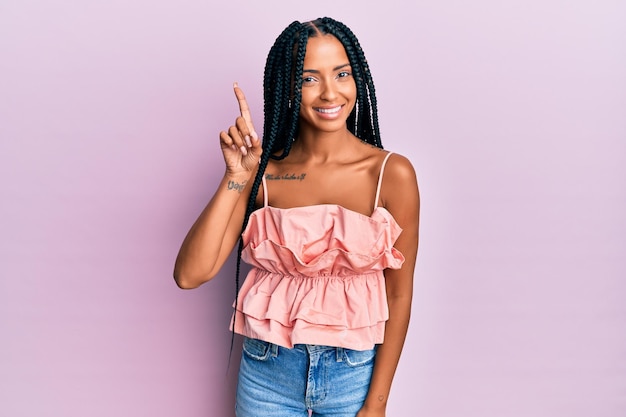 Beautiful hispanic woman wearing casual clothes smiling with an idea or question pointing finger up with happy face, number one