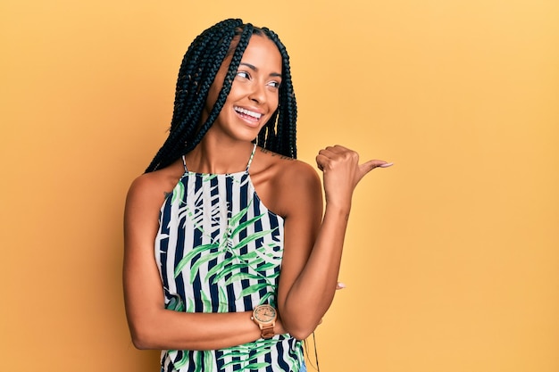 Photo beautiful hispanic woman wearing summer dress smiling with happy face looking and pointing to the side with thumb up.