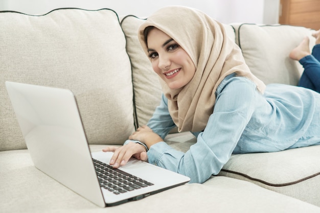 Hijab를 입고 아름 다운 주부는 노트북에 브라우징을 즐길 수