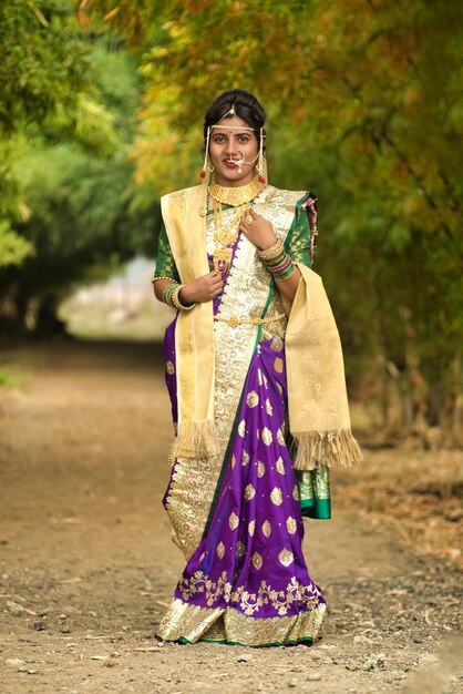 Foto bella sposa indiana in saree tradizionale che posa all'aperto nel parco