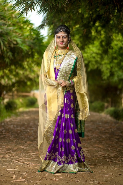 Photo beautiful indian bride in traditional saree posing outdoors park