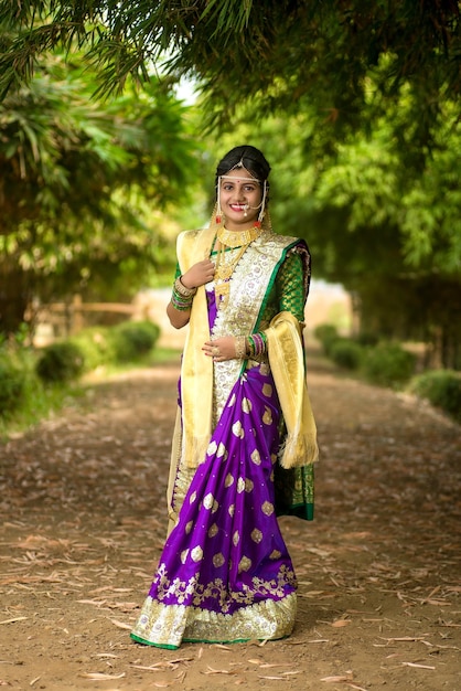 Foto bella sposa indiana in saree tradizionale che posa all'aperto nel parco