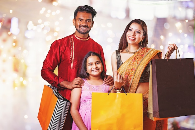 モールで贈り物と買い物袋を保持している美しいインドの家族