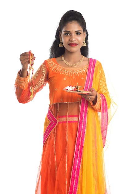 Beautiful Indian girl showing Rakhi with pooja thali on occasion of Raksha Bandhan.