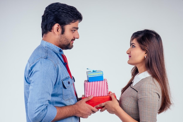 Beautiful indian woman and handsome turkey man giving gift boxes in studio white background.New year or Ekadashi deepawali concept.