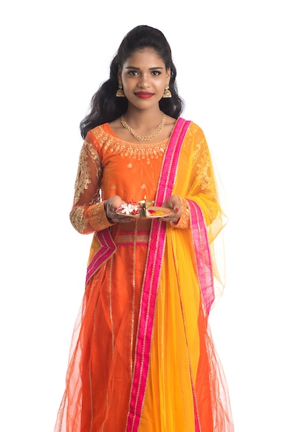 Beautiful Indian young girl holding pooja thali or performing worship on white