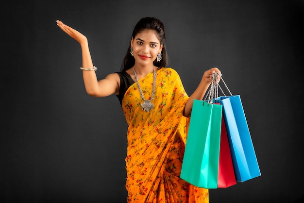 Beautiful Indian young girl holding and posing with shopping bags on a grey background