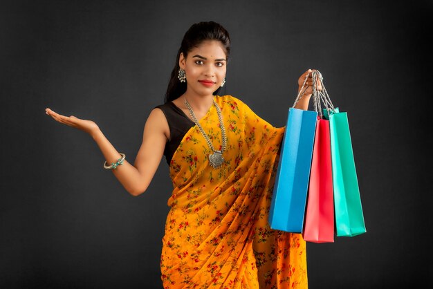 Beautiful Indian young girl holding and posing with shopping bags on a grey background