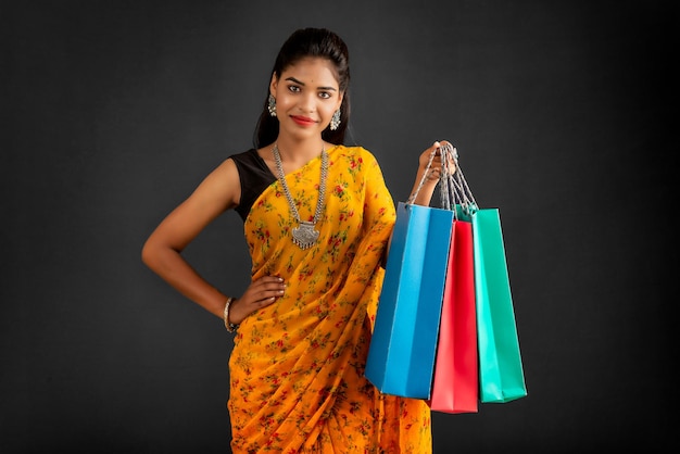 Beautiful Indian young girl holding and posing with shopping bags on a grey background