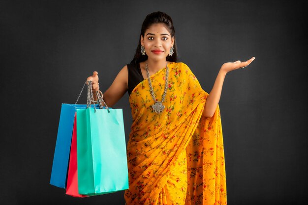 Beautiful Indian young girl holding and posing with shopping bags on a grey background