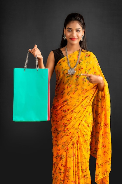 Beautiful Indian young girl holding and posing with shopping bags on a grey background