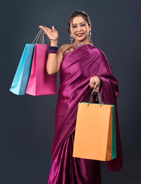 Beautiful Indian young girl holding and posing with shopping bags on a grey background