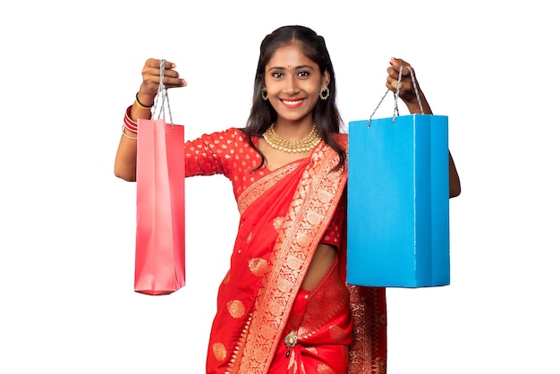 Beautiful Indian young girl holding and posing with shopping bags on a white background