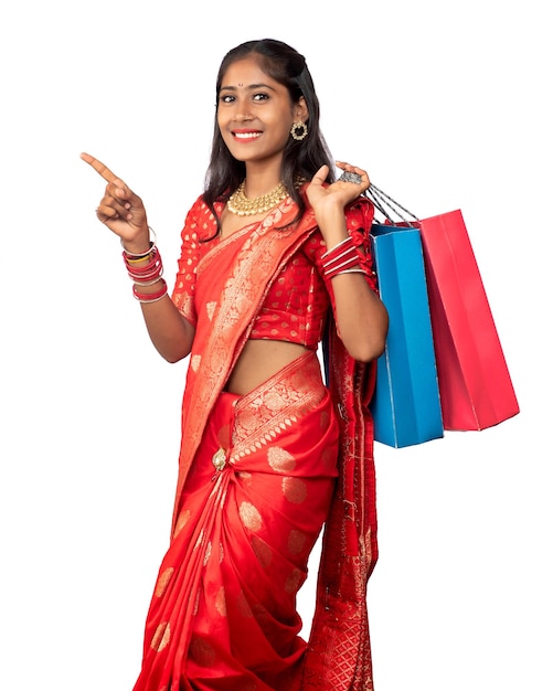 Beautiful Indian young girl holding and posing with shopping bags on a white background