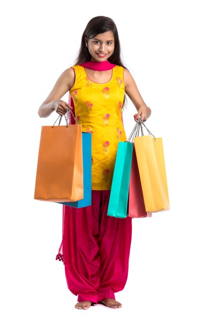 Beautiful Indian young girl holding and posing with shopping bags on a white space