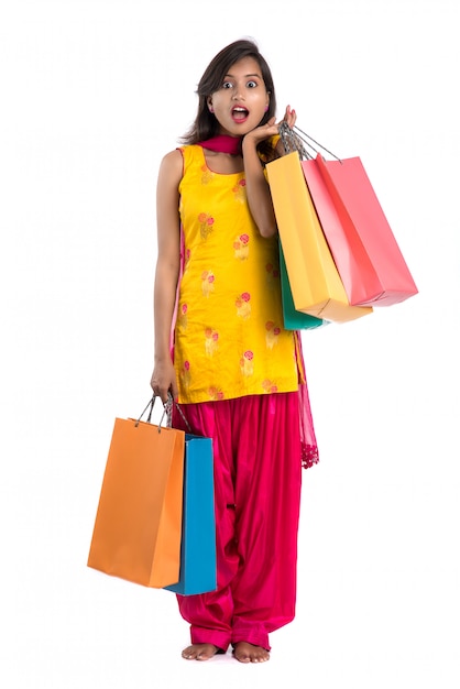 Beautiful Indian young girl holding and posing with shopping bags on a white space