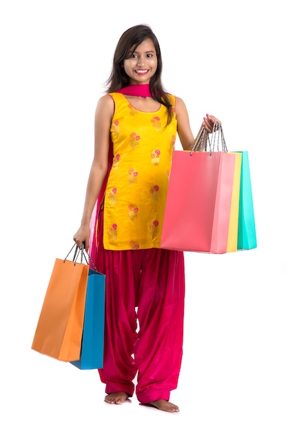 Beautiful Indian young girl holding and posing with shopping bags on a white