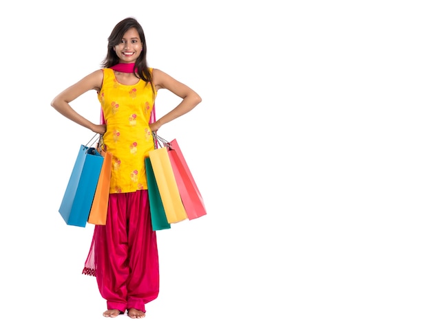 Beautiful Indian young girl holding and posing with shopping bags on a white