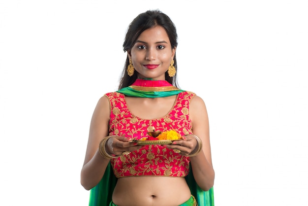 Beautiful Indian young woman holding pooja thali or performing worship on white