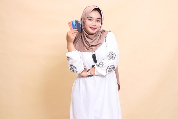 a beautiful indonesia Muslim girl wearing a hijab with a crooked smile and her arms holding a debit