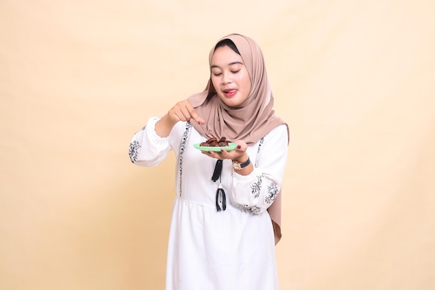 A beautiful indonesia Muslim woman wearing a hijab with a delicious expression picks and brings some