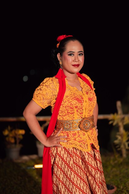 Beautiful Indonesian women wearing an orange traditional dance costume called kebaya when dancing a danced called jaipong