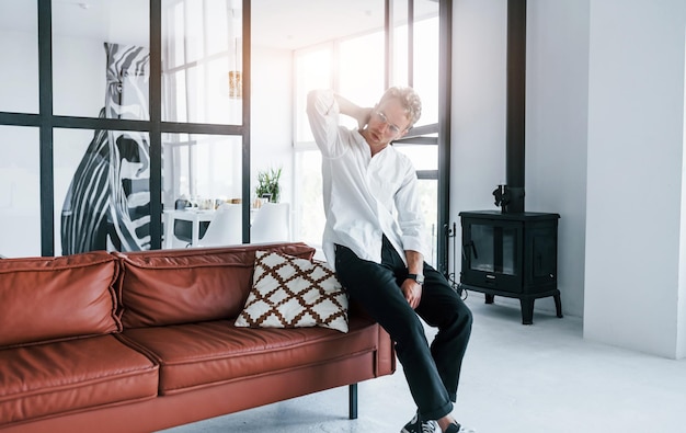 Beautiful interior Caucasian young guy in elegant white shirt indoors at home