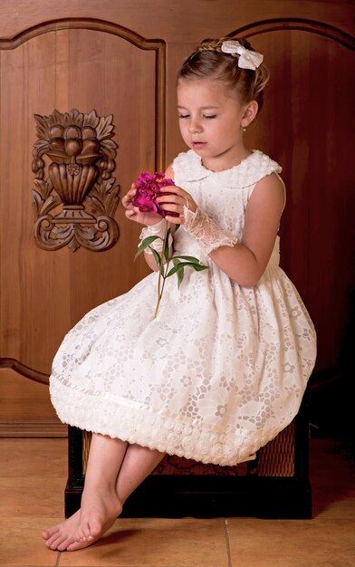 Beautiful interior of a modern house Elegant girl in a white dress Girl holding fresh peonies bouquet on wooden background