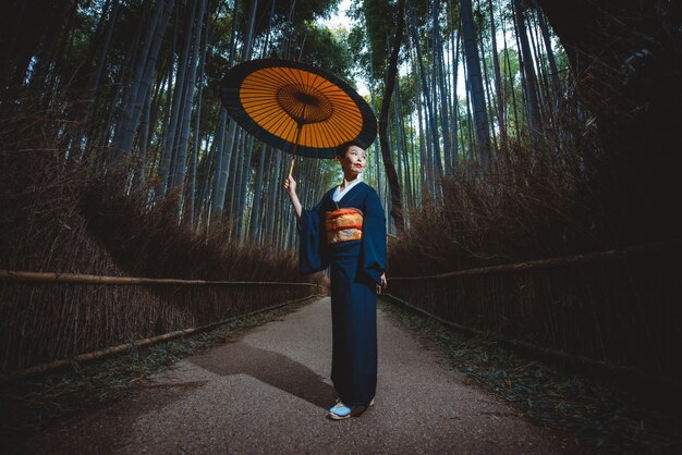 竹の森を歩く美しい日本の年配の女性