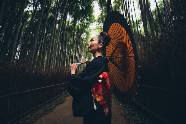 Красивая японская старшая женщина гуляя в бамбуковый лес