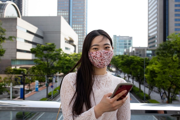 写真 都会の環境で医療マスクを持つ美しい日本人女性