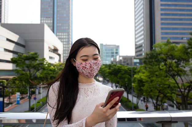 都会の環境で医療マスクを持つ美しい日本人女性