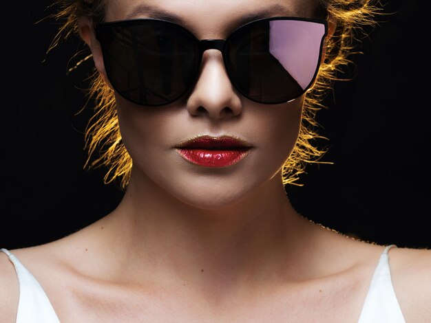 Beautiful joyful young woman in sunglasses bright lips with red lipstick portrait on black