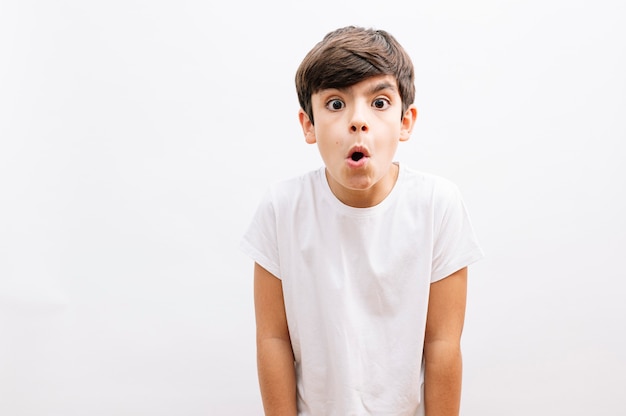Beautiful kid boy wearing casual t-shirt standing over isolated white background afraid and shocked with surprise expression, fear and excited face.