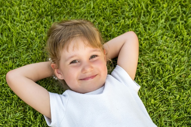 Beautiful kid laying on the grass in the park