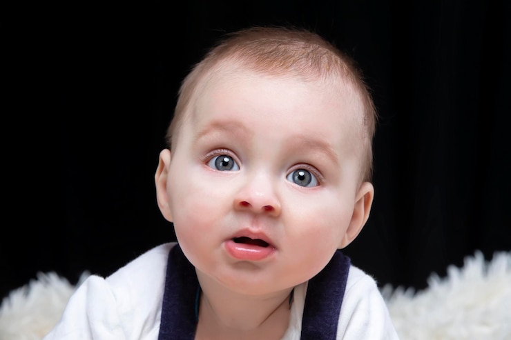 A beautiful kid looks at the camera in surprise. Baby at four months old. A funny child.