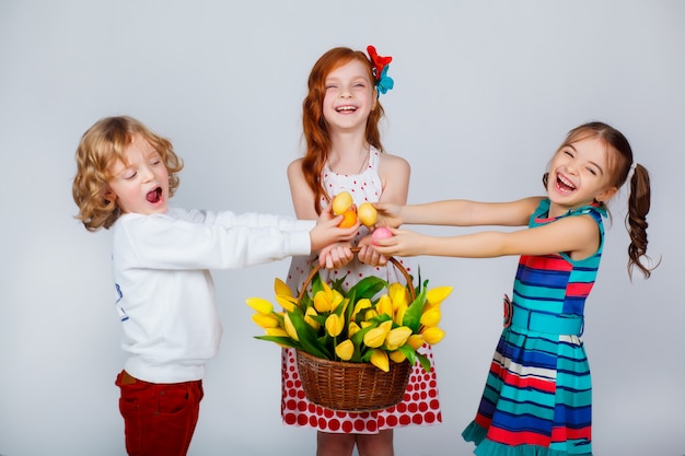 Beautiful kids with a basket of tulips and Easter eggs are having fun.  Funny moments