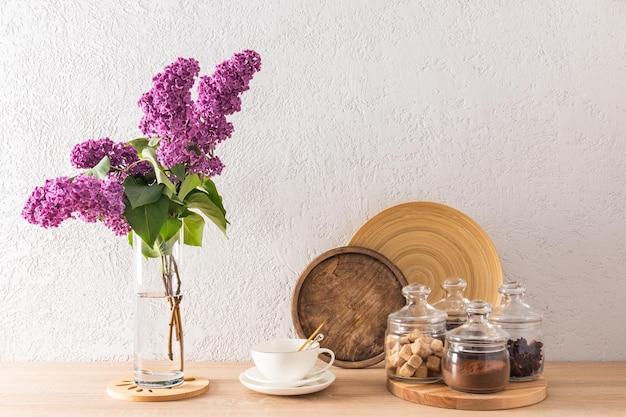 beautiful kitchen background with glass jars for storing tea coffee sugar and a cup against of a gray textured wall a vase of flowers